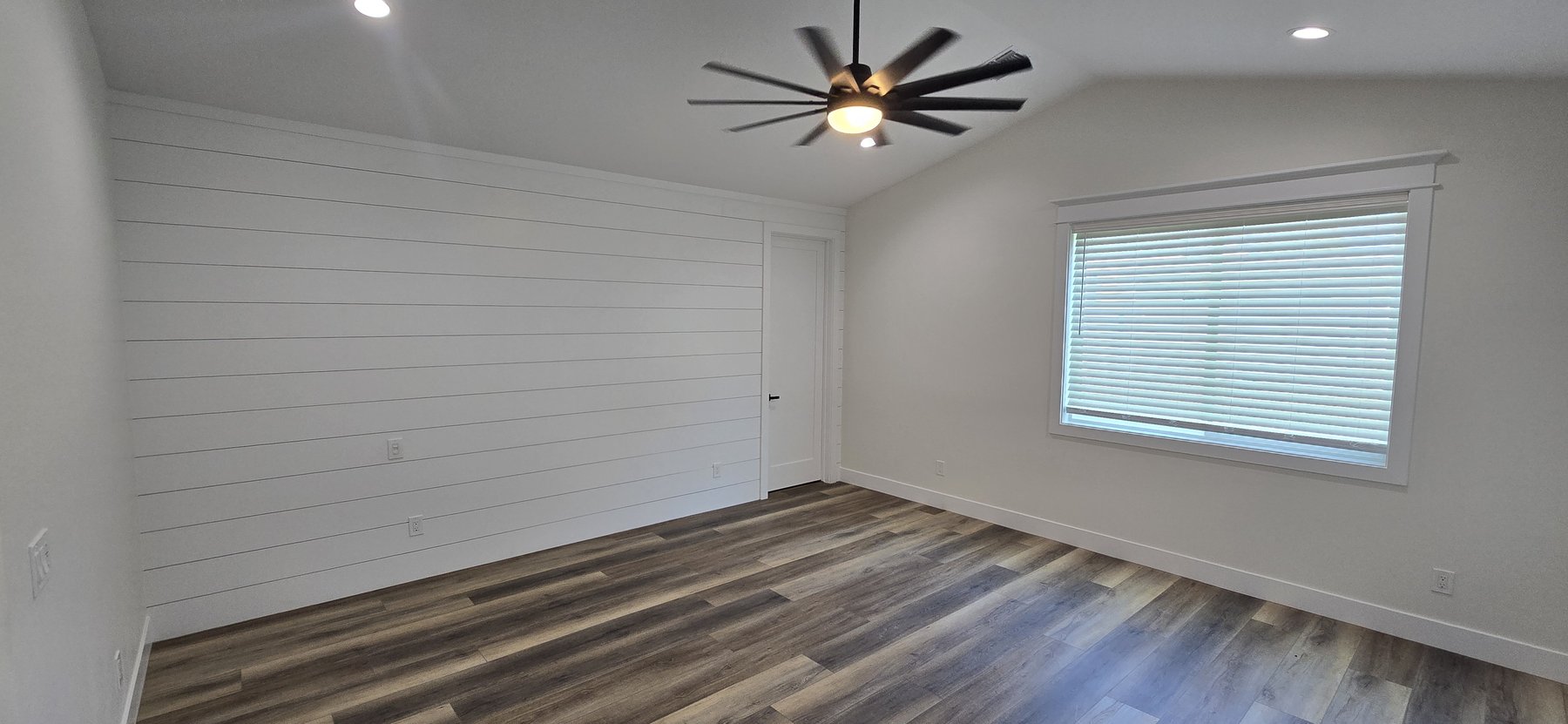 Real photo of primary bedroom with vaulted shiplap accent wall